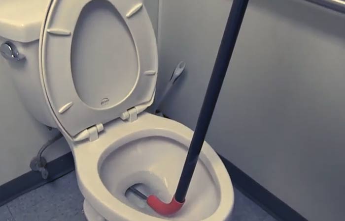 inserting auger in a toilet bowl